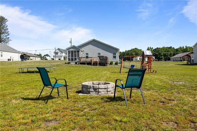 308 Laurel Lake Rd, Salemburg, NC 28385 - view of grassy yard featuring a trampoline, a fire pit, a playground, a sunroom, and a wooden deck