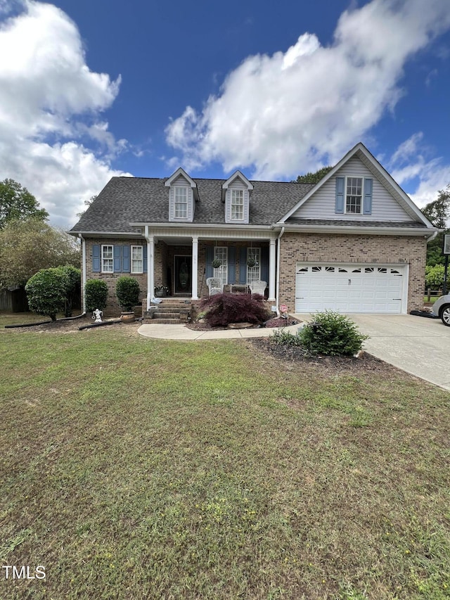view of front of property with driveway, a front yard, brick siding, covered porch, and roof with shingles