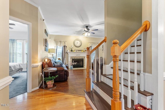 151 Donnibrook Run, Fuquay Varina, NC 27526 - staircase featuring a ceiling fan, wood finished floors, a fireplace with flush hearth, and a wainscoted wall