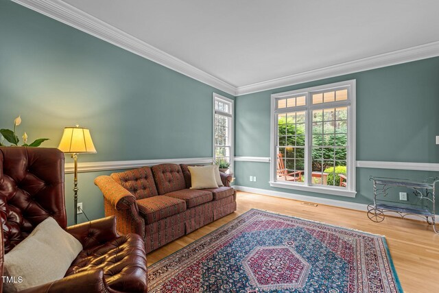 living room featuring wood finished floors, ornamental molding, and baseboards