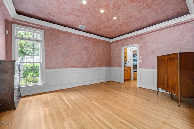 unfurnished room featuring crown molding, a wainscoted wall, light wood-style flooring, and recessed lighting