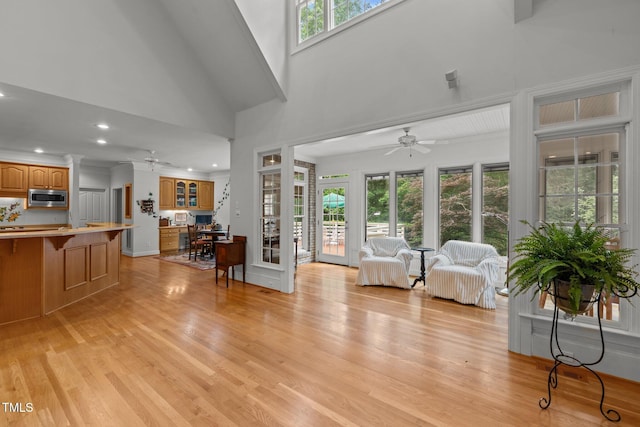 living area featuring ceiling fan, light wood-style flooring, recessed lighting, and a high ceiling