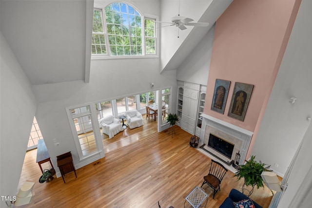 living room featuring a high ceiling, a fireplace, wood finished floors, and ceiling fan