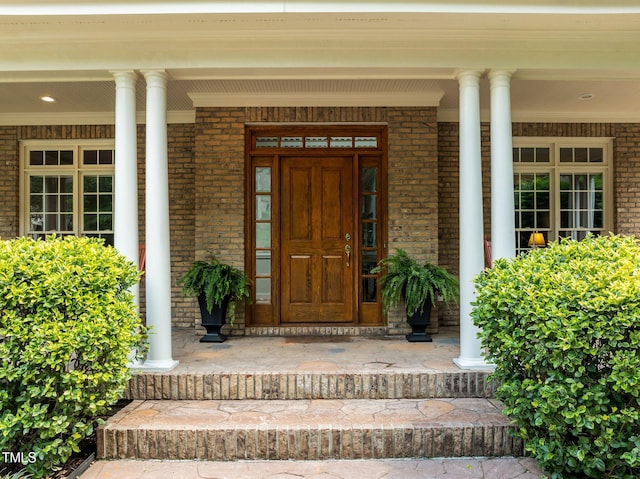 entrance to property with a porch and brick siding