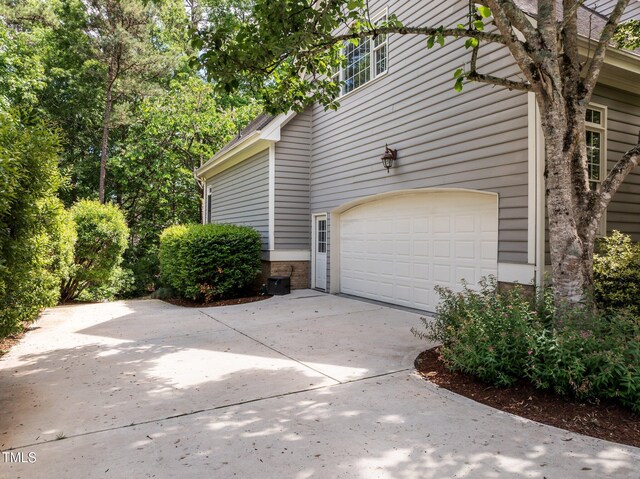 view of side of home featuring concrete driveway, a garage, and brick siding
