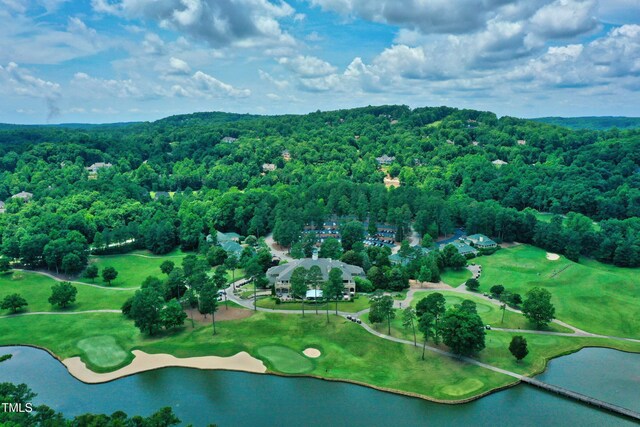 bird's eye view of a forest, a nearby body of water, and a golf course