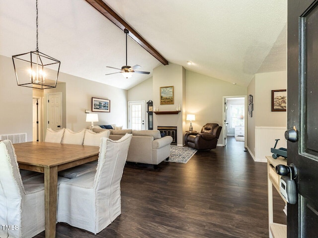 dining space with dark wood-type flooring, a ceiling fan, a glass covered fireplace, and a chandelier