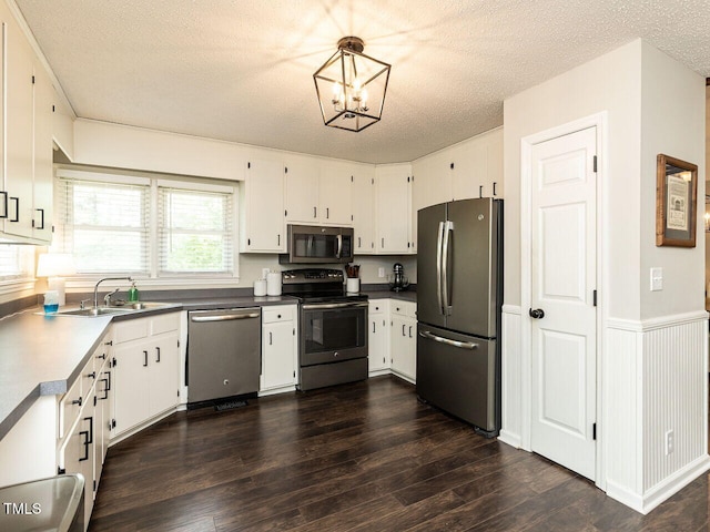 kitchen with stainless steel appliances, a sink, a textured ceiling, dark wood-style floors, and white cabinetry