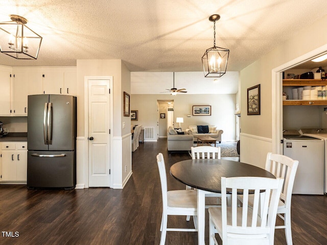 dining area featuring washer and clothes dryer, a chandelier, dark wood-style flooring, a ceiling fan, and a textured ceiling