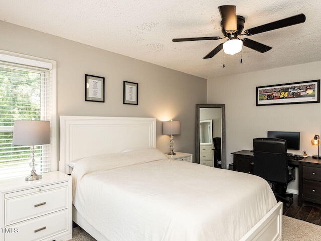 bedroom featuring dark wood-style floors, a textured ceiling, ceiling fan, and a desk