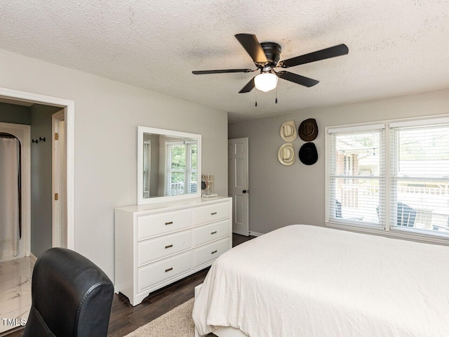 bedroom with a textured ceiling, a ceiling fan, and dark wood-style flooring