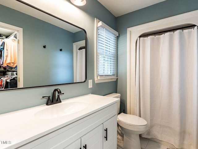 bathroom with toilet, vanity, a walk in closet, and curtained shower