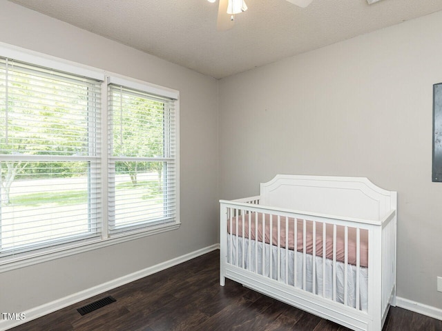 bedroom featuring baseboards, dark wood-type flooring, and a crib