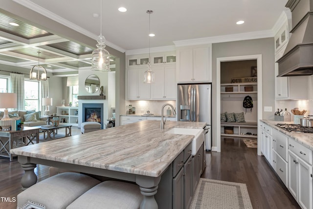 kitchen featuring custom exhaust hood, appliances with stainless steel finishes, dark wood-style flooring, white cabinets, and ornamental molding
