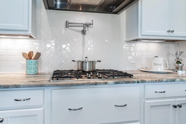 kitchen with stainless steel gas stovetop, extractor fan, tasteful backsplash, white cabinetry, and light stone countertops