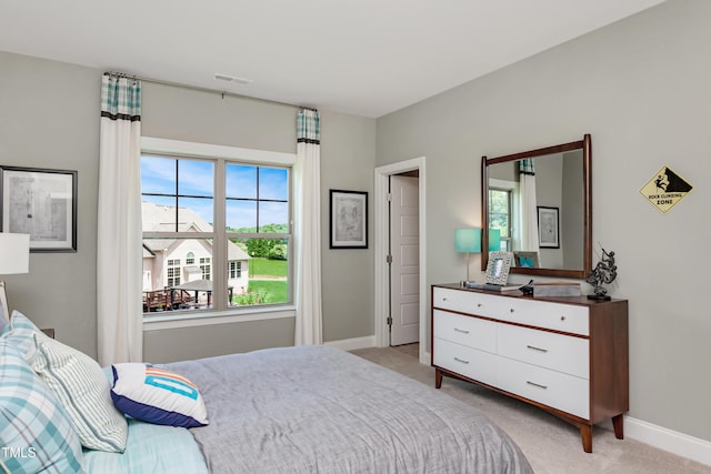bedroom with light carpet, multiple windows, and baseboards