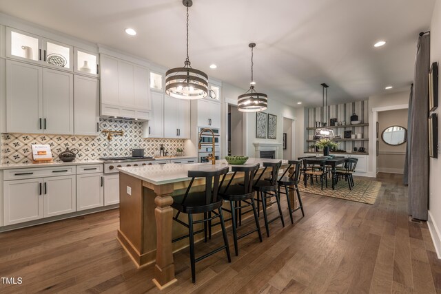 318 Ivy Ridge Rd, Chapel Hill, NC 27516 - kitchen with stainless steel gas stovetop, backsplash, white cabinetry, an island with sink, and recessed lighting