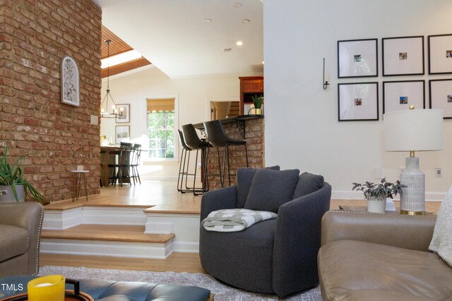 living area with wood finished floors, baseboards, a chandelier, and lofted ceiling