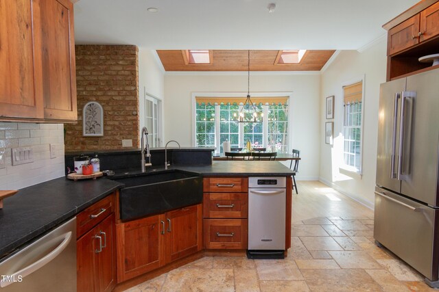 kitchen featuring appliances with stainless steel finishes, crown molding, a sink, a peninsula, and decorative backsplash