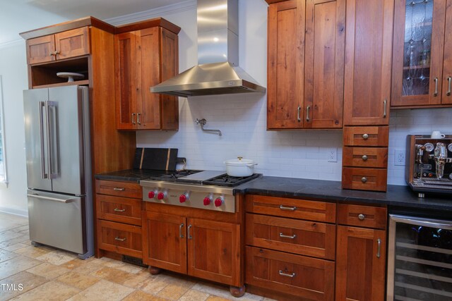 kitchen with stainless steel appliances, wall chimney exhaust hood, wine cooler, brown cabinetry, and dark countertops