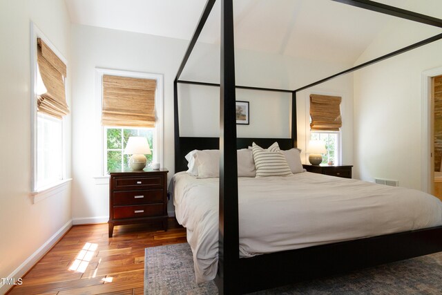 bedroom featuring wood finished floors, baseboards, and vaulted ceiling