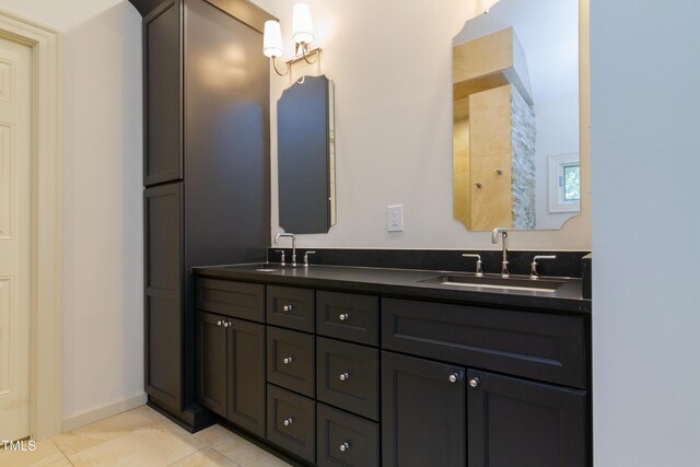 full bath featuring double vanity, tile patterned flooring, and baseboards
