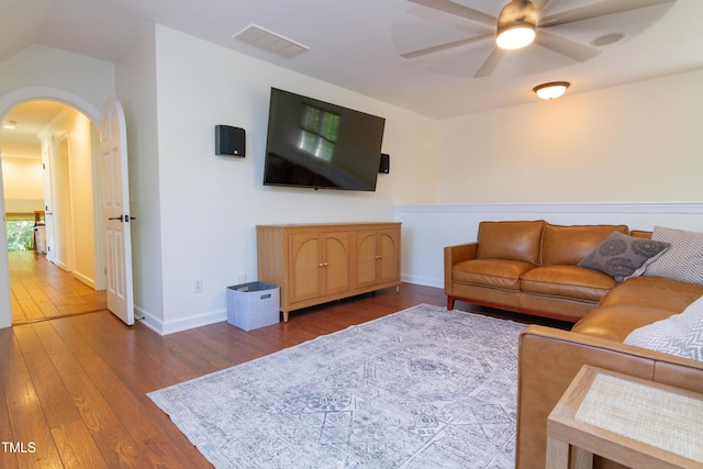 living area featuring arched walkways, ceiling fan, wood-type flooring, and baseboards