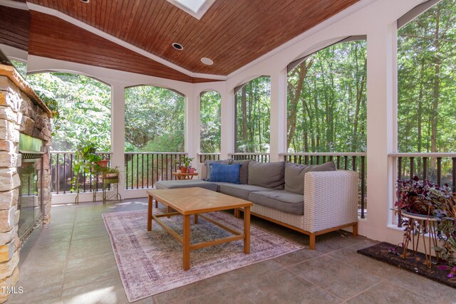sunroom / solarium with wooden ceiling, lofted ceiling, an outdoor hangout area, healthy amount of natural light, and a skylight