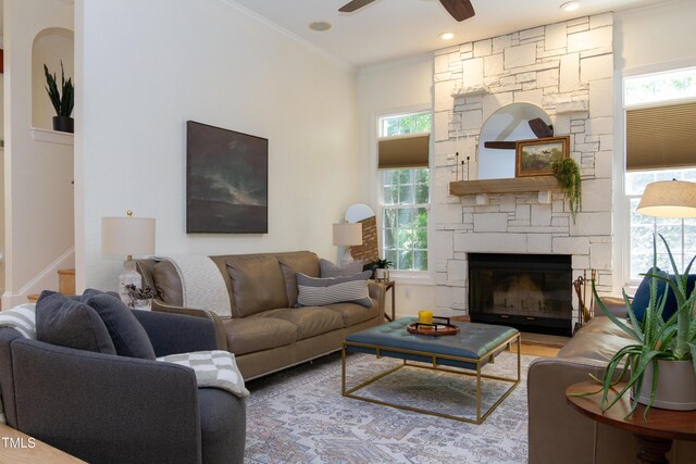living room with plenty of natural light, ceiling fan, crown molding, a fireplace, and stairway