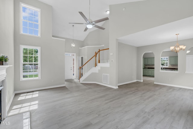 8820 Waynick Dr, Raleigh, NC 27617 - unfurnished living room featuring high vaulted ceiling, a premium fireplace, stairway, ceiling fan, and a chandelier