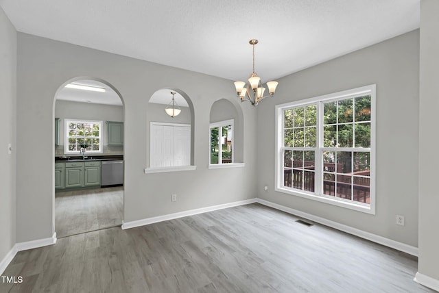 8820 Waynick Dr, Raleigh, NC 27617 - unfurnished dining area featuring wood finished floors, a chandelier, baseboards, and arched walkways