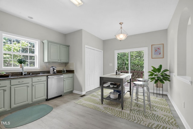 8820 Waynick Dr, Raleigh, NC 27617 - kitchen with dishwasher, a sink, baseboards, light wood-type flooring, and dark countertops