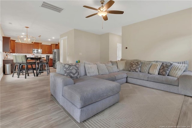 living area featuring ceiling fan, light wood-style floors, a chandelier, and recessed lighting