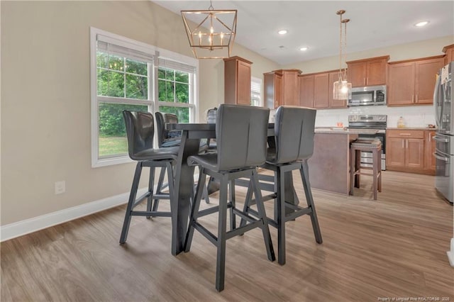 dining area featuring plenty of natural light, light wood-type flooring, baseboards, a chandelier, and recessed lighting