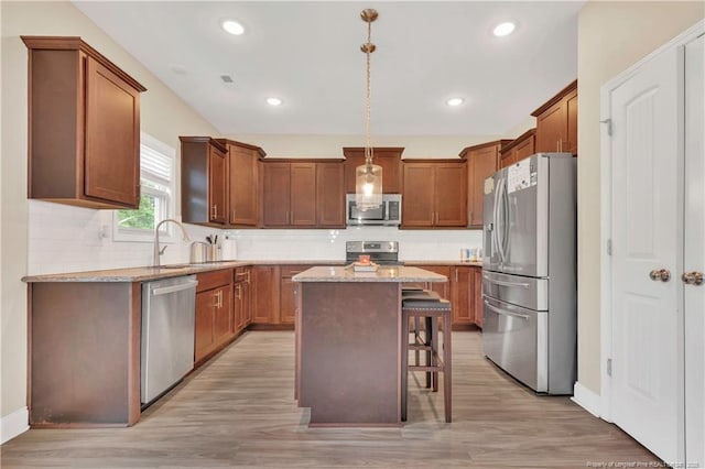 kitchen featuring appliances with stainless steel finishes, light stone countertops, a kitchen breakfast bar, a center island, and recessed lighting