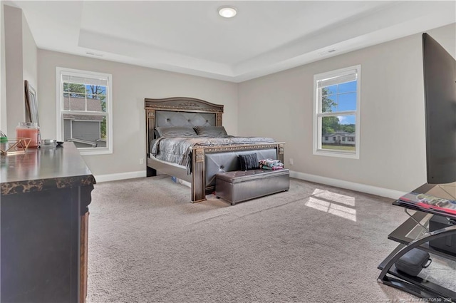 carpeted bedroom with a tray ceiling and baseboards