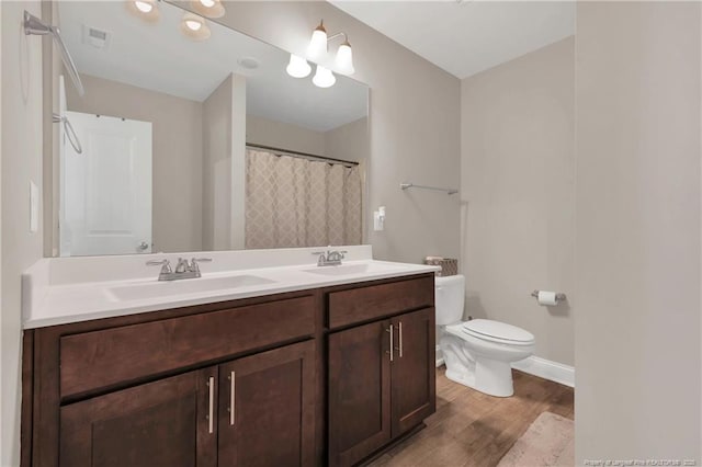 full bath with wood finished floors, toilet, double vanity, and baseboards