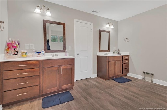 full bath with wood finished floors, two vanities, and baseboards