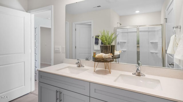 full bath with a stall shower, double vanity, and recessed lighting
