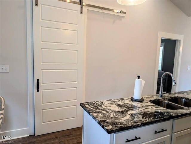 3904 Lundin Dr, Greensboro, NC 27407 - kitchen featuring a sink, dark stone countertops, a barn door, dark wood-style floors, and white cabinets