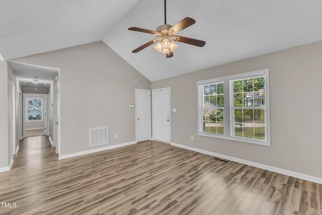 unfurnished living room featuring light wood-style floors, attic access, ceiling fan, high vaulted ceiling, and baseboards