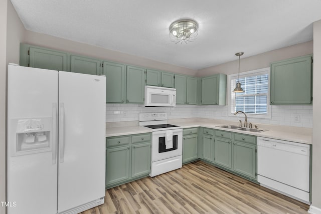 kitchen featuring white appliances, a sink, tasteful backsplash, and light wood-style flooring