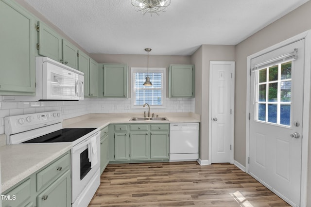 kitchen featuring white appliances, a sink, green cabinets, healthy amount of natural light, and a textured ceiling