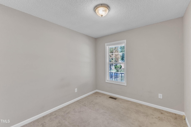 carpeted empty room with baseboards and a textured ceiling
