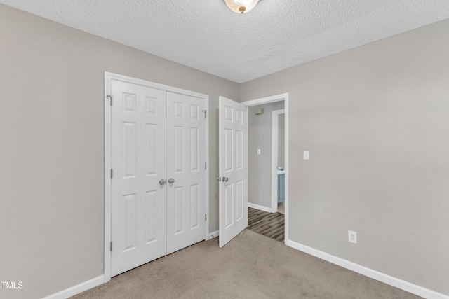unfurnished bedroom featuring carpet, a closet, baseboards, and a textured ceiling