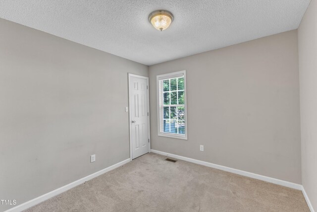 carpeted spare room with baseboards and a textured ceiling