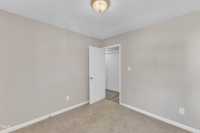 spare room featuring baseboards, carpet flooring, and a textured ceiling