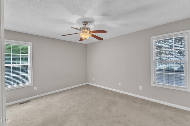 empty room with a ceiling fan, carpet floors, baseboards, and a textured ceiling