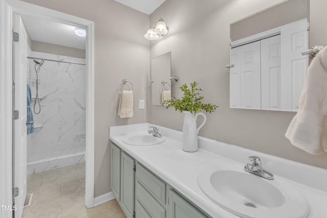 full bath with a marble finish shower, double vanity, marble finish floors, and baseboards