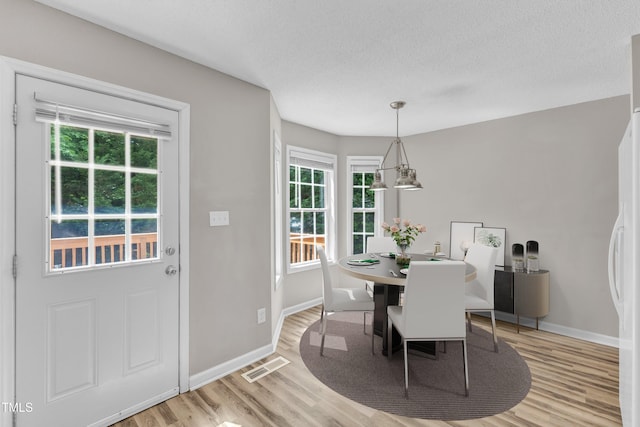 dining area with light wood-style floors, baseboards, and a textured ceiling